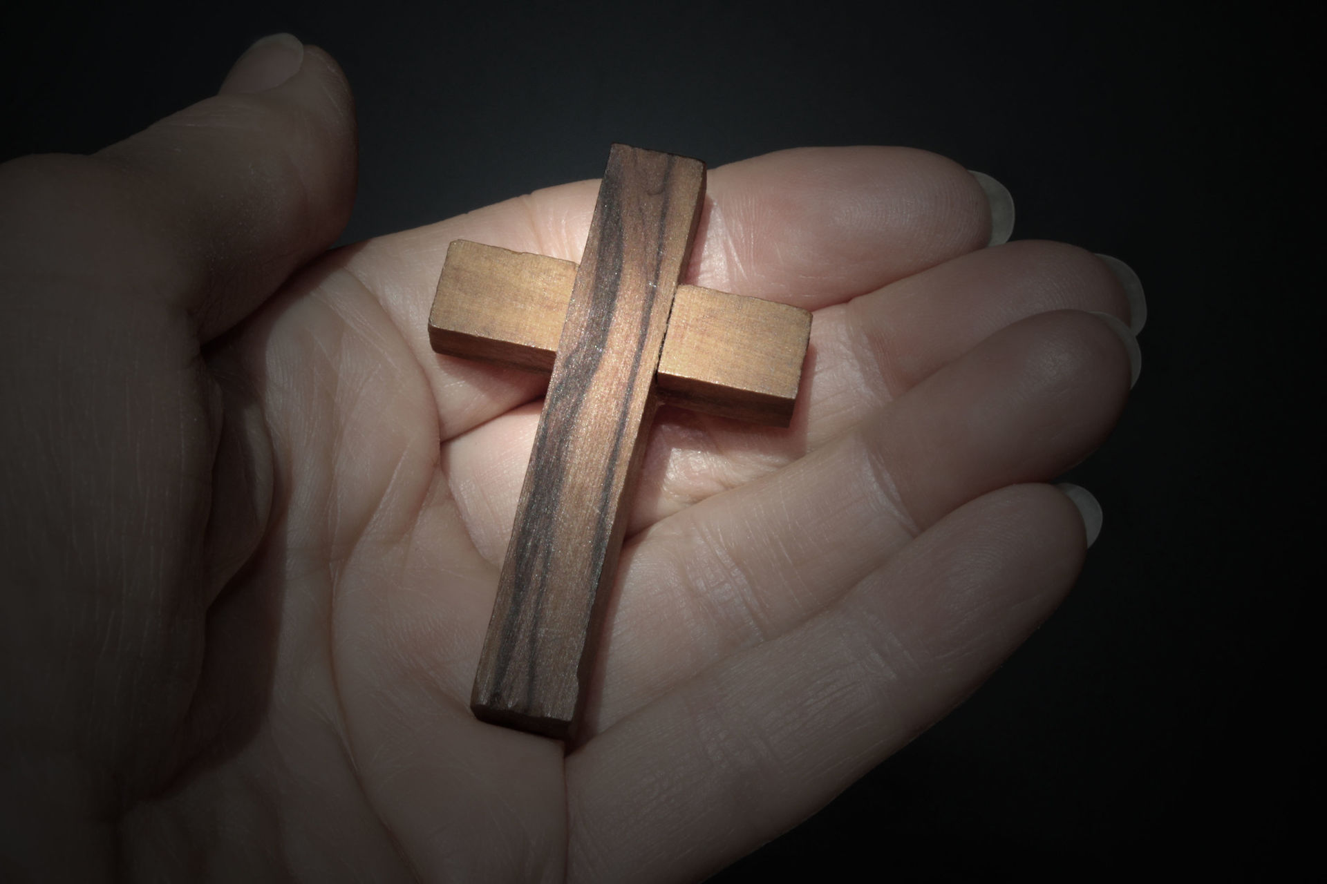 Ein Holzkreuz in einer Hand.